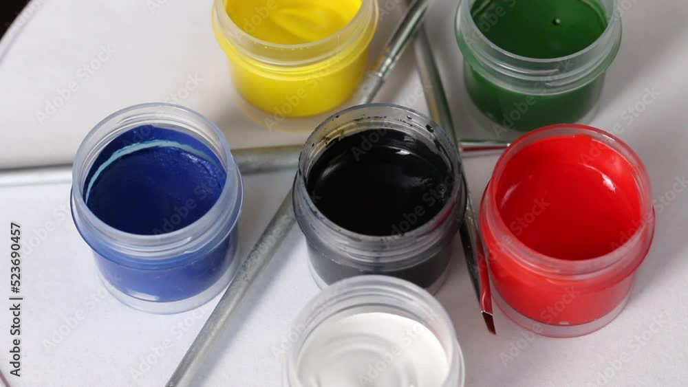 A set of gouache and brushes. Open cans of paint. Rotate on the subject table. Close-up. A set of gouache and brushes. Open cans of paint. Rotate on the subject table. Close-up.