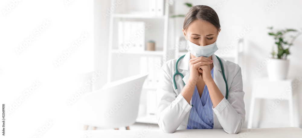 Praying female doctor in clinic. Banner for design Praying female doctor in clinic. Banner for design