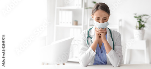 Praying female doctor in cl...