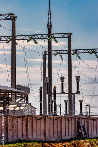 Close-up of electrical substation showing wires, ceramic insulators and birds nesting beneath them.