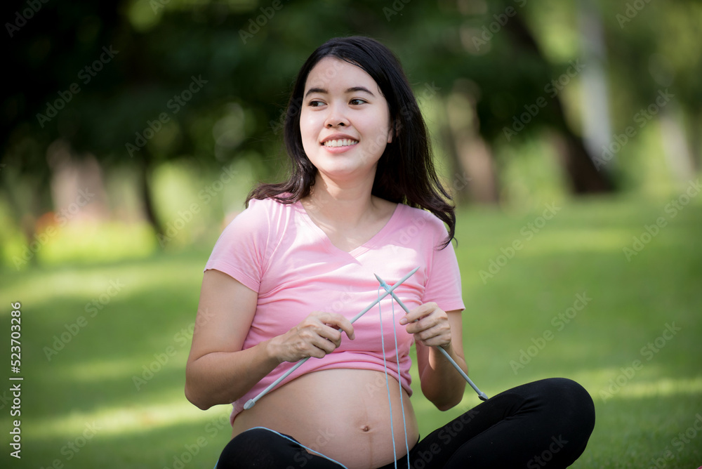 Pregnancy, People and Healthy Lifestyle - Happy pregnant woman knitting baby in the park. concept of what is going to happen Pregnancy, People and Healthy Lifestyle - Happy pregnant woman knitting baby in the park. concept of what is going to happen