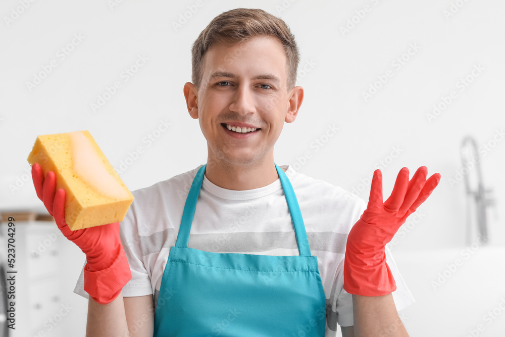 Young man with cleaning sponge in bathroom Young man with cleaning sponge in bathroom
