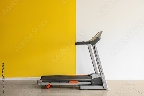 Modern treadmill near yello...
