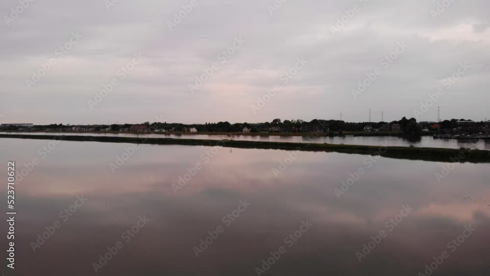Calm Reflective Tranquil Sunset Over River Beside Crezeepolder Nature Reserve. Aerial Pedestal Up Calm Reflective Tranquil Sunset Over River Beside Crezeepolder Nature Reserve. Aerial Pedestal Up