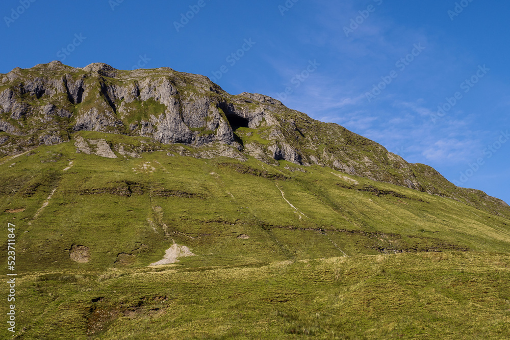 Mountains and green fields with sheep in Gleniff horseshoe drive, county Sligo, Ireland. Warm sunny day. Clean blue sky. Popular tourist location with amazing nature scenery. Irish landscape.