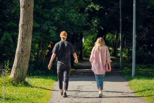 Fototapeta Naklejka Na Ścianę i Meble -  Couple walking in a park and keeping some distance. Date concept. Friend zone.