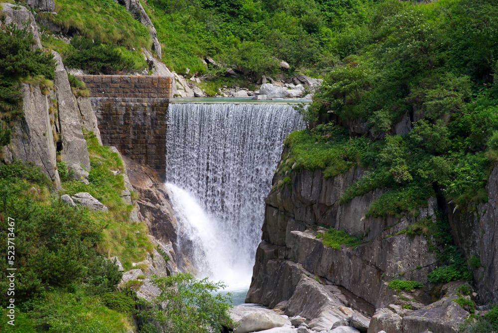 Narrow famous Schöllenen Gorge with Reuss River and beautiful scenic view of waterfall on a sunny summer day. Photo taken July 3rd, 2022, Andermatt, Switzerland.