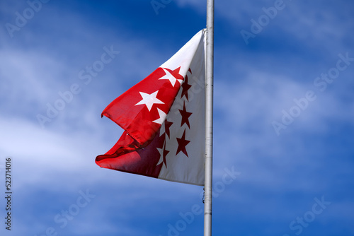 Canton Valais flag blowing in the wind at summit of Swiss mountain pass Nufenen on a sunny summer day. Photo taken July 3rd, 2022, Nufenen Pass, Switzerland.