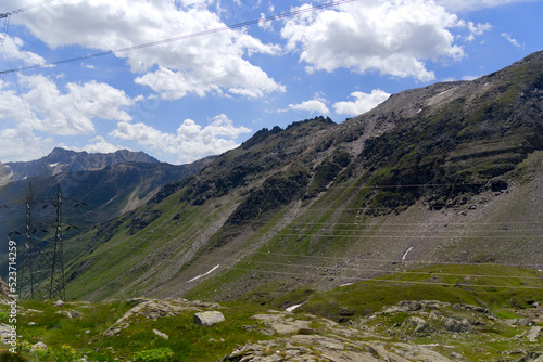 Scenic view of Bedretto Valley, Canton Ticino, with power line pylons at Nufenen Pass on a sunny summer day. Photo taken July 3rd, 2022, Val Bedretto, Switzerland.