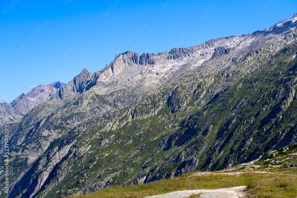 Scenic view of mountain panorama seen from summit of Swiss mountain pass Grimsel on a sunny summer day. Photo taken July 3rd, 2022, Grimsel Pass, Switzerland.
