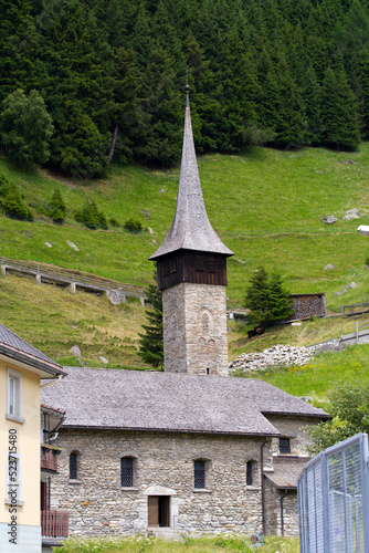 Roman style stone church named St. Kolumban at Swiss mountain village on a sunny summer day. Photo taken July 3rd, 2022, Andermatt, Switzerland.