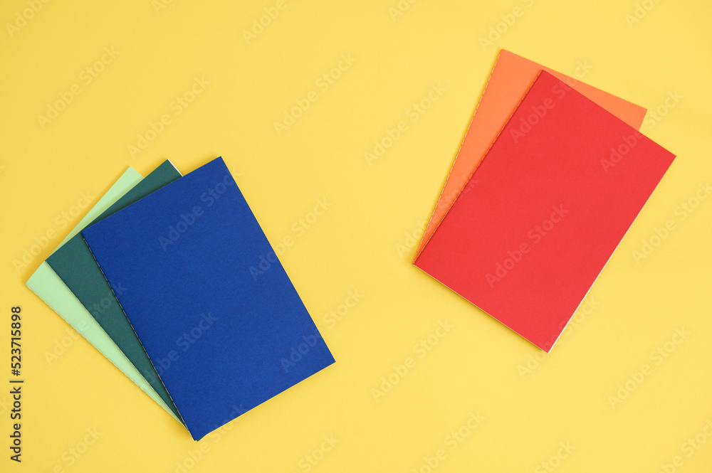 notebooks in different colors on bright yellow background from above notebooks in different colors on bright yellow background from above