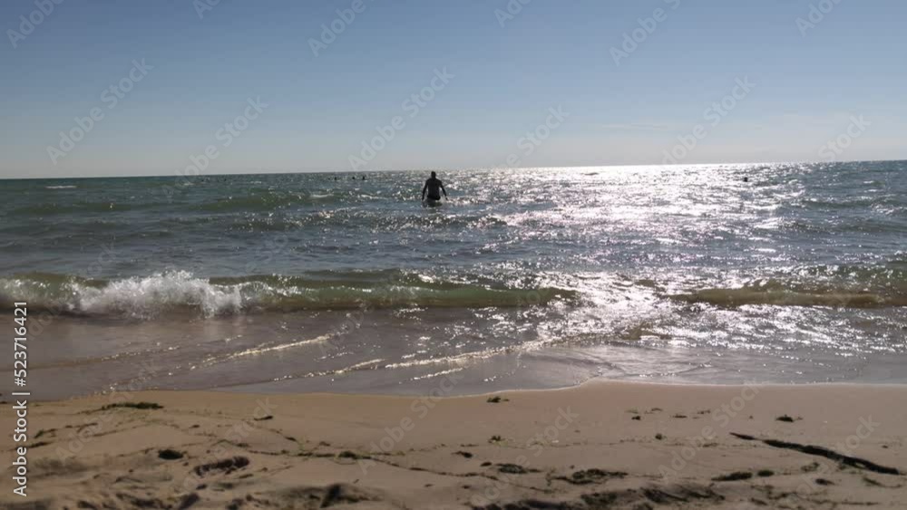 Caucasian middle aged male walking in swimsuit out of Lake Michigan water on the beach. Caucasian middle aged male walking in swimsuit out of Lake Michigan water on the beach.