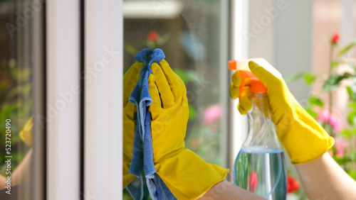 Woman applying detergent spray and rag for cleaning window outside