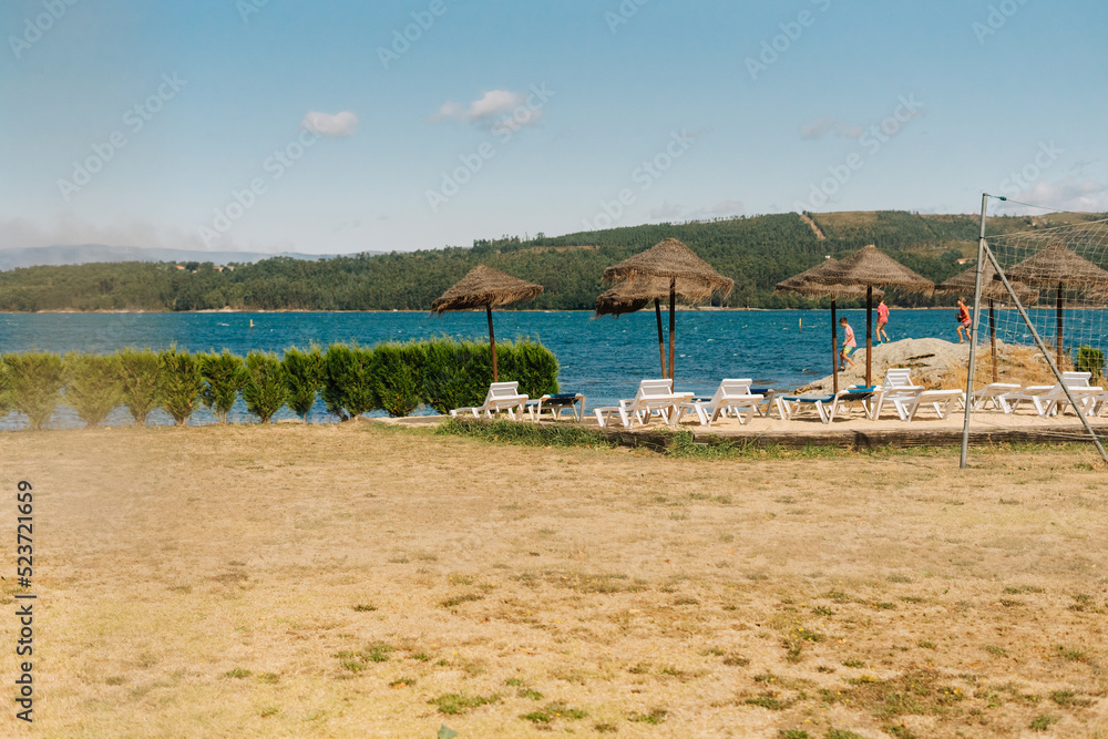 Natural solarium with deck chairs and straw parasols near the river