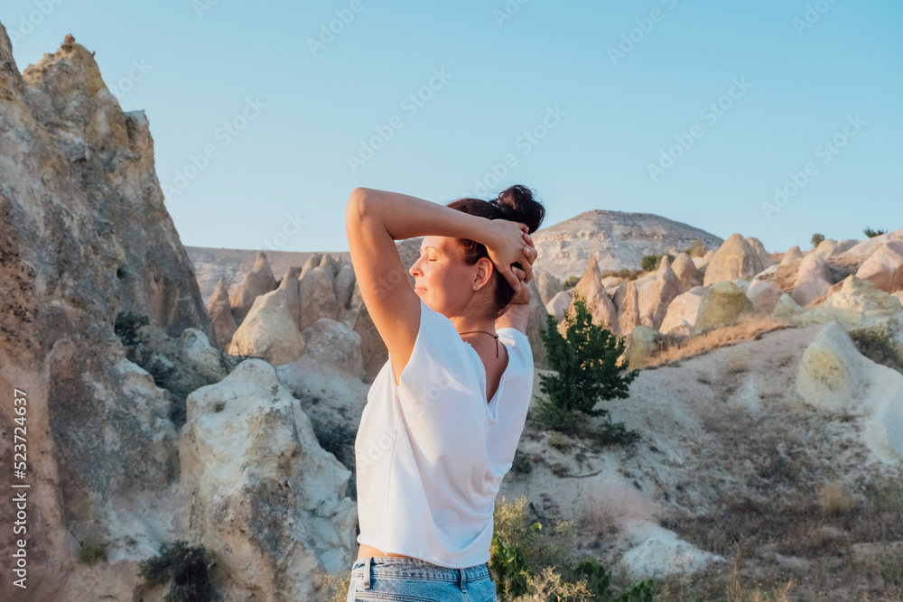 Back view of girl enjoying Cappadocia mountain view during sunset. Traveler woman admiring the sunset.