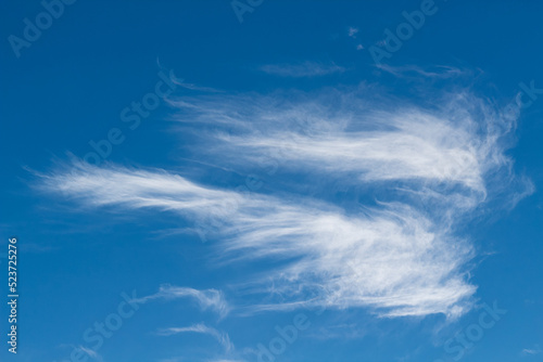 Beautiful thin cirrus clouds. White spindrift clouds in a shape of an angel on blue sky photo