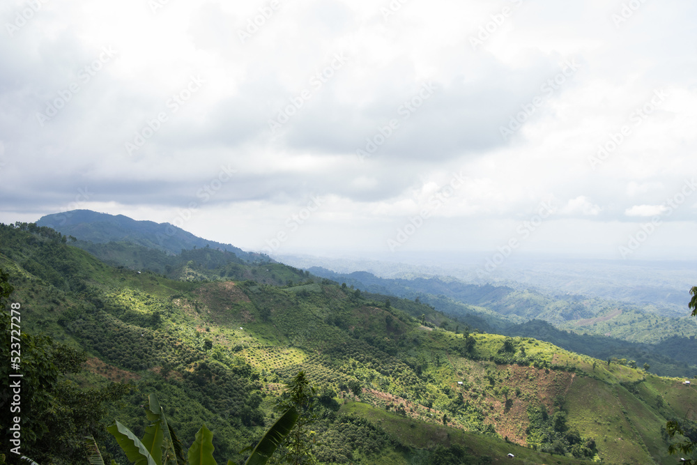 Rural mountain view with cloudy sky and hilly jungle. Green hilltop view with a drone. Hiking trail landscape photograph of hills. Beautiful hill station photo at Bandarban, Bangladesh.