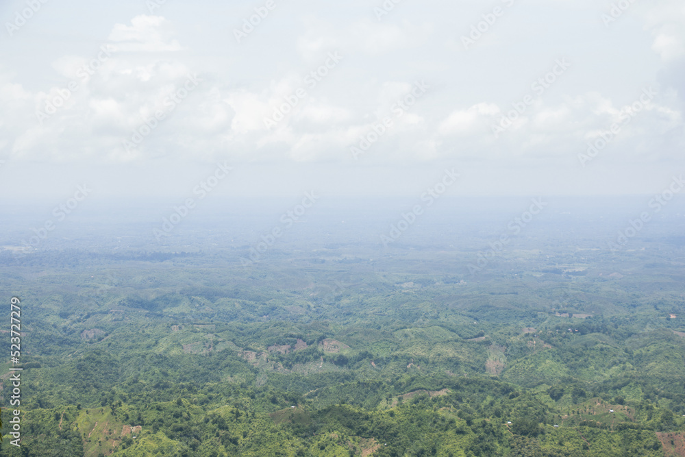 Hilly landscape aerial view photography with cloudy sky. Foggy weather and mountain top view with a drone. Beautiful nature photo of hilly meadow and beautiful sky. Hill jungle and green fields.