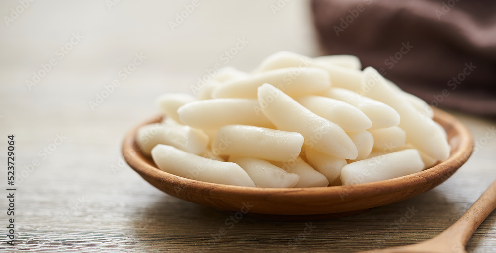 Tteok or Korean Rice Cakes in a wooden plate on wood table background Tteok or Korean Rice Cakes in a wooden plate on wood table background