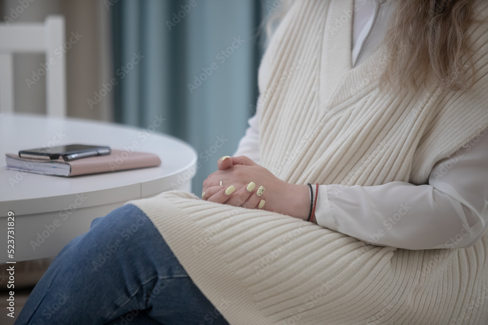 Confident woman sits with folded arms at work table closeup