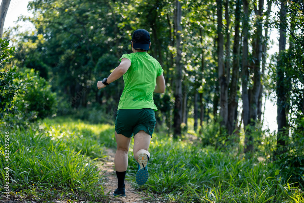 Woman trail runner running at tropical forest mountain peak Woman trail runner running at tropical forest mountain peak
