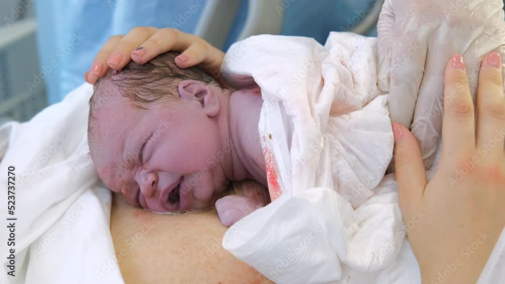 Young mother holding newborn child after labor. Emotional moment of child birth in maternity hospital Young mother holding newborn child after labor. Emotional moment of child birth in maternity hospital