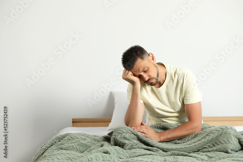 Photos Sleep deprived man sitting on bed at home. Space for text