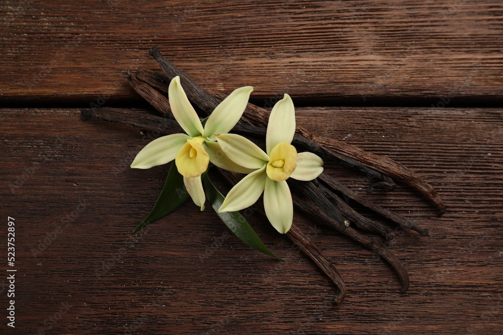 Beautiful vanilla flowers and sticks on wooden table, flat lay Beautiful vanilla flowers and sticks on wooden table, flat lay