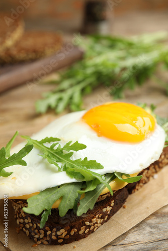 Delicious sandwich with arugula and egg on wooden table, closeup