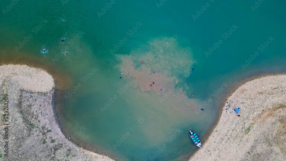 Aerial view Mangla Lake or river drone shot, Boat or ship standing at riverbank or lake shore with people swimming, pakistani or indian or south asian drone shot video 