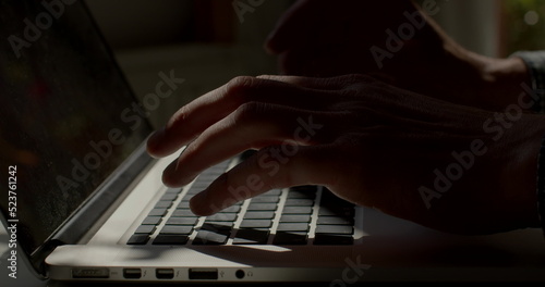 Light spot on a laptop keyboard. He presses buttons, prints text. Writing a letter using a computer. Finger movement using keys. A straight row of buttons in quick typing.