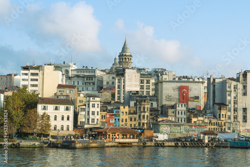 Galata Tower with old houses, Karaköy pier and sea view. Cloudy sky.