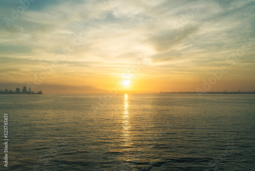 Sunset over the sea, sun in the middle of horizon, building horizon on the edges. © A.Serdar K