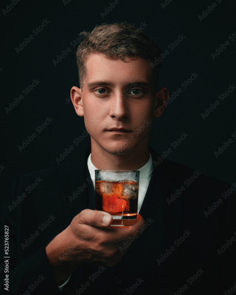 Tasting, tasting. A man in a suit holds a glass of brandy. Tasting and wine tasting concept. Young businessman in an elegant suit with a glass of whiskey. Sommelier tastes an expensive drink. Tasting, tasting. A man in a suit holds a glass of brandy. Tasting and wine tasting concept. Young businessman in an elegant suit with a glass of whiskey. Sommelier tastes an expensive drink.