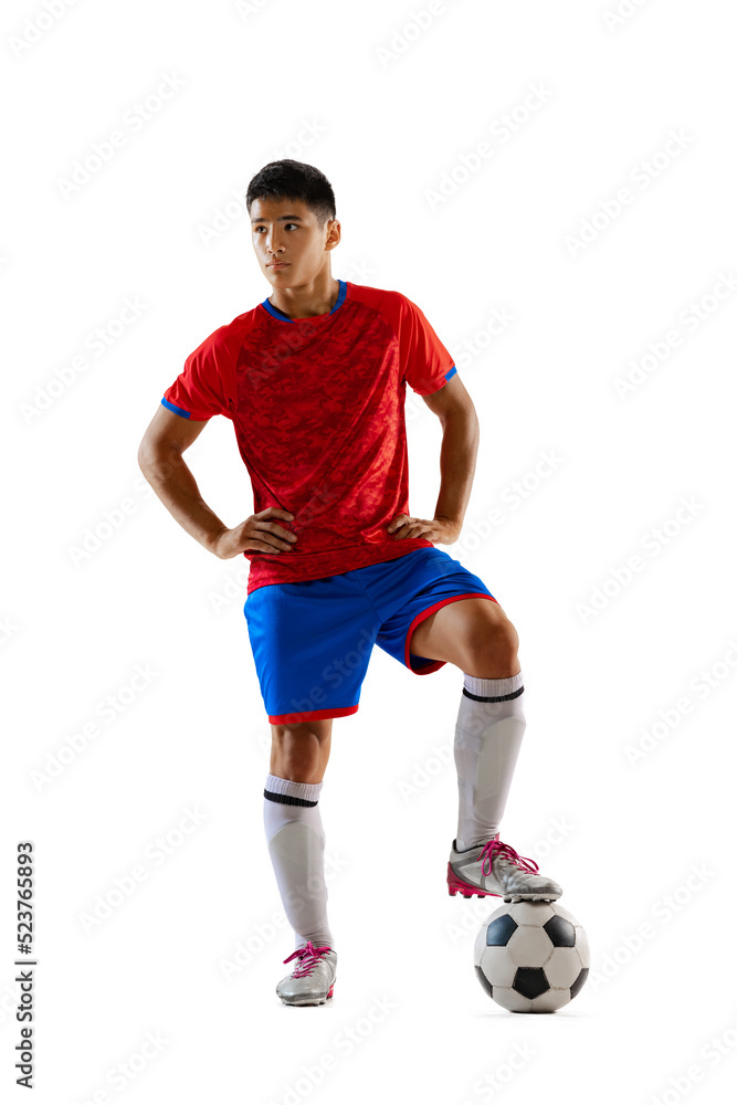 Portrait of proud young man, football player in uniform posing with ball isolated over white studio background
