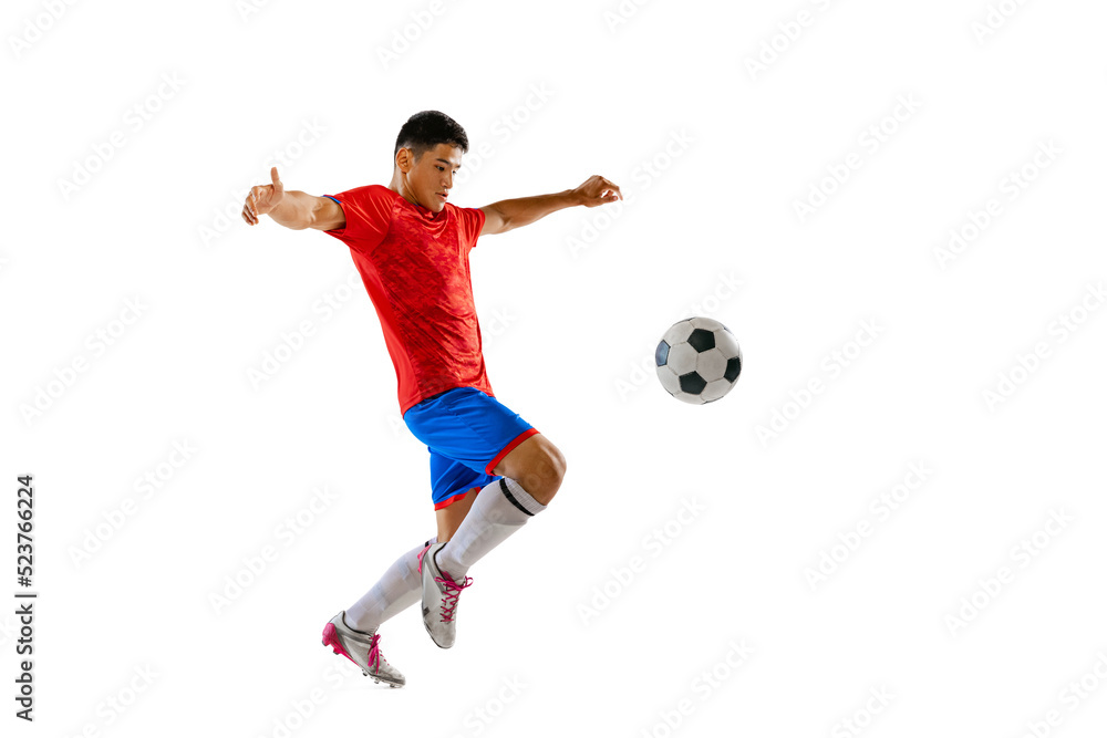 Portrait of young man, football player training, playing, kicking ball isolated over white studio background. Motivation
