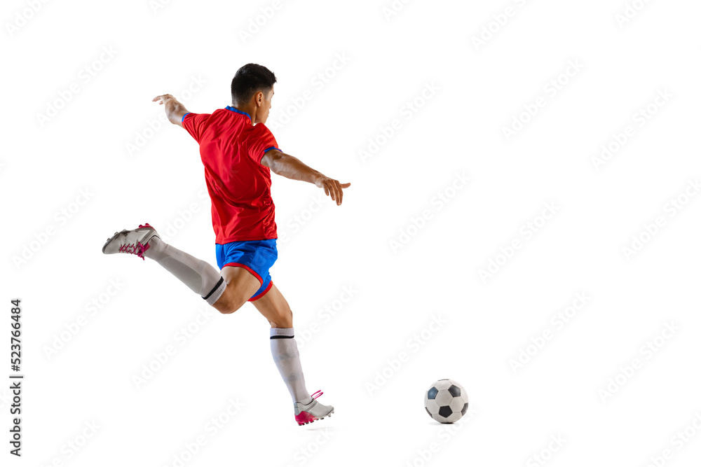 Dynamic portrait of young man, professional football player in motion, training, dribbling ball isolated over white studio background