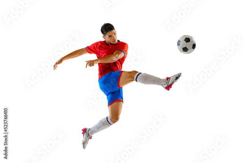 Portrait of young man in uniform, professional football player kicking ball in a jump isolated over white studio background.