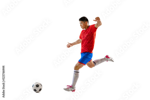Dynamic portrait of young man, professional football player in motion, training, dribbling ball isolated over white studio background