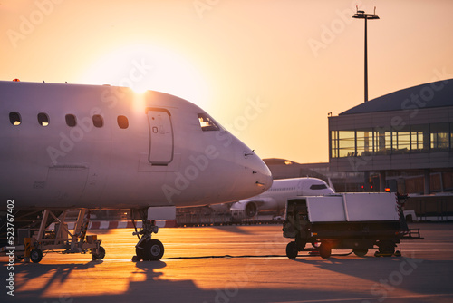 Preparation of airplanes before flight. Airport at golden sunrise. photo