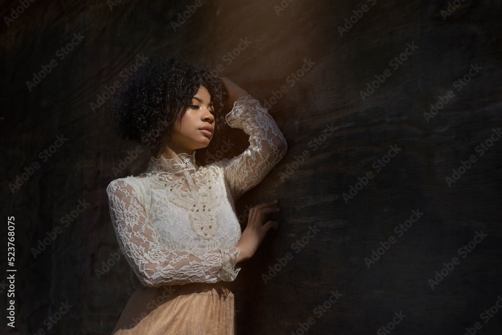 Dreamy calm ethnic lady leaning on wall in studio