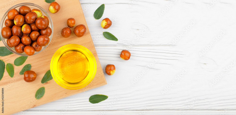 Fresh ripe jojoba fruit and jojoba oil in bowl on wooden table, banner Fresh ripe jojoba fruit and jojoba oil in bowl on wooden table, banner