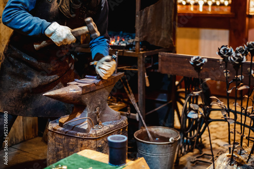 blacksmith is forging a souvenir horseshoe on a city street fair