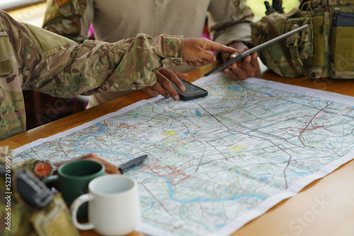 Army ranger military special force hold a cup drink coffee discussion looking pointing at the war map on table and GPS to mark up location plan before attact enemy

