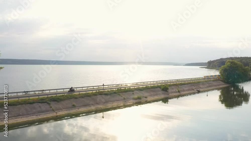 Wallpaper Mural Aerial view to biker riding on motorbike at dam route with sunshine at background. Motorcyclist racing his motorcycle through road near lake. Man drive bike during trip. Concept of adventure. Top view Torontodigital.ca
