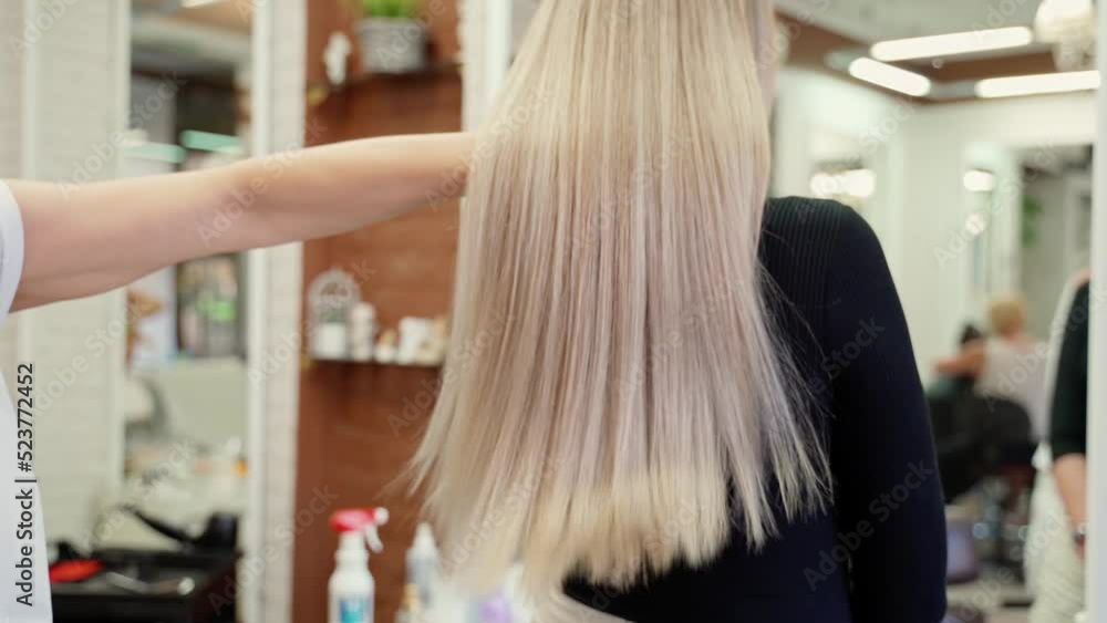 the hairdresser's hands run through the smooth, beautiful, dark and very long blond hair of a young beautiful woman. the hairdresser's hands run through the smooth, beautiful, dark and very long blond hair of a young beautiful woman.