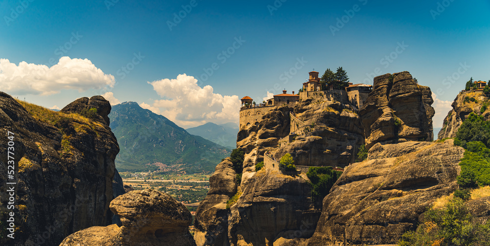 Traveling concept. Panoramic shot of the beautiful combination between nature and human. Impressive architecture of Meteora monasteries in Greece seen from afar. High quality photo