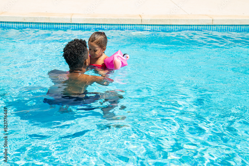 Mixed race father and daughter having fun in pool