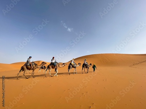 Tourists riding camels in the Sahara desert © Phurinutc